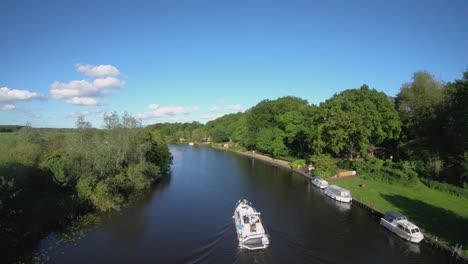 Aerial-Drone-Footage-of-a-boat-sailing-along-the-River-Yare,-Norfolk