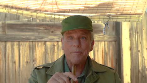 Attractive-elderly-man-talking-and-looking-around-while-holding-a-cuban-cigar