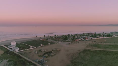 Aerial-Drone-shot-flying-over-a-small-city-in-mexico-to-the-ocean-just-after-the-sun-has-set