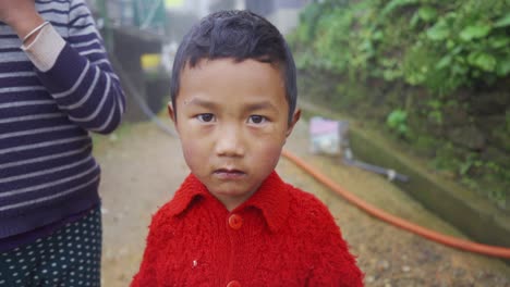 Poor-Asian-male-child-looks-at-camera-moving-forward-at-foggy-morning,-slow-motion