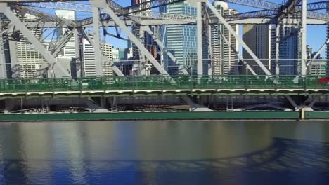 Aerial-shot-of-Story-Bridge-at-road-level,-as-the-drone-moves-along-with-the-traffic-and-the-Brisbane-Riverside-precinct-can-be-seen-in-the-background