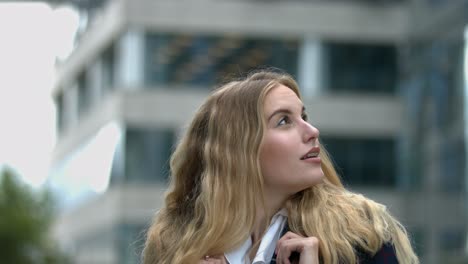 close-up-of-young-student-businesswoman-behind-building-looking-intently-around-with-confidence-and-a-big-smile