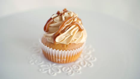 One-peanut-flavor-muffin-cupcake-rotating-slowly-on-decorated-white-plate