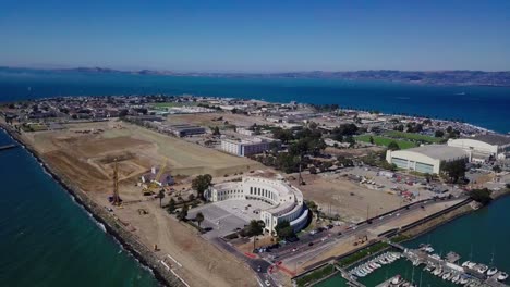 4k-aerial-drone-view-of-treasure-island-san-francisco-bay-area-surrounded-by-turquoise-blue-ocean-sea-water-waves-camera-move-back-away