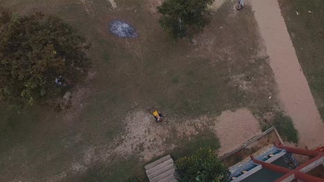 Aerial-shot-ascending-above-little-Vietnam-boy-lying-on-ground-outside