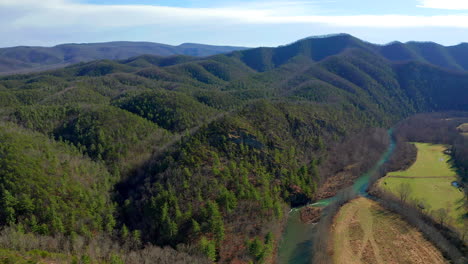 Drone-Shot-of-River-Valley-Over-Mountains-and-Rockface-Cliffs-into-Forest