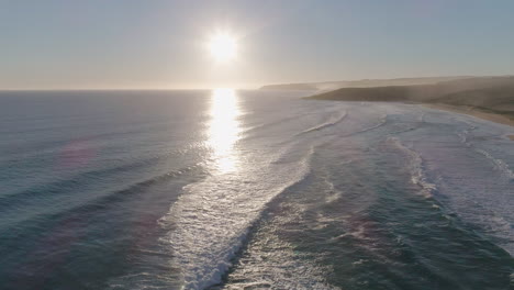 Rising-aerial-shot-of-waves-crashing-into-shore-at-sunset-in-South-Australia