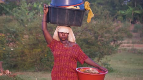Close-up-slow-motion-shot-of-an-African-woman-balancing-bucket-load-of-clothes-on-her-head-in-rural-Africa