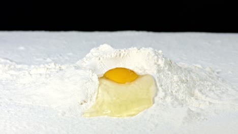 Footage-of-an-Egg-Being-in-Some-Flour,-Against-a-Black-Background