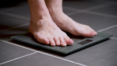 Man-steps-on-a-home-scale,-checks-his-weight,-and-steps-back-off