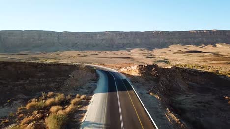 aerial:-drone-view-over-a-deserted-road-in-the-middle-of-the-Ramon-crater-canyons,-Makhtesh-Ramon-in-Israel