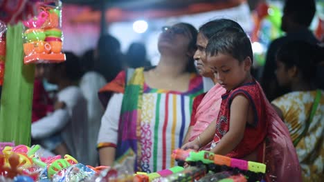 Eine-Indische-Frau-Mit-Ihrem-Kind-In-Einem-Spielzeugladen-Auf-Einem-Festival