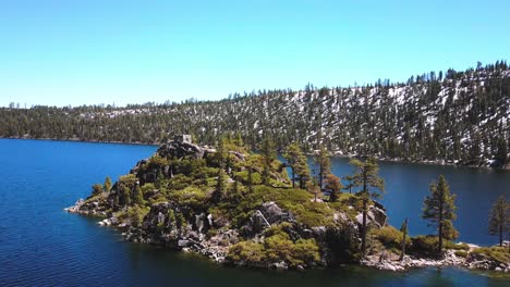 Aerial-drone,-Lake-Tahoe-at-Emerald-Bay,-flying-up-to-island,-snow-mountains,-sunny-day,-Nevada,-USA