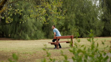 Man-sits-on-a-park-bench-relaxing-looking-at-his-smart-phone-then-gets-up-and-walks-away