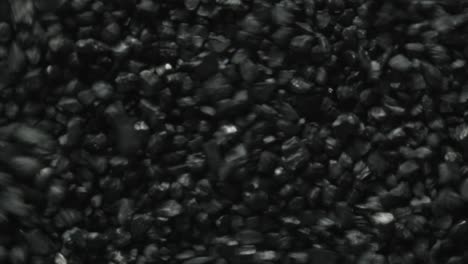 Macro-shot-of-black-coal-stones-shaking-and-moving-forward-through-vibrations-of-sound