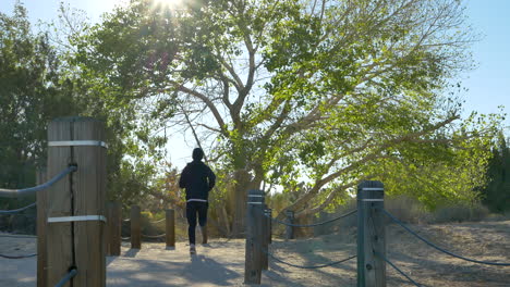 A-young-fit-white-man-on-a-cold-fall-morning-jog-after-a-workout-running-away-from-the-camera-through-a-peaceful-desert-nature-preserve