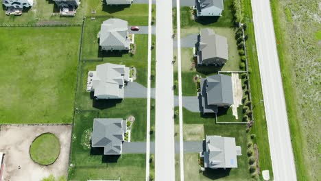 Aerial-shot-of-a-neighborhood-with-modern-family-homes-on-one-side-and-a-not-so-busy-urban-road-on-the-other-side