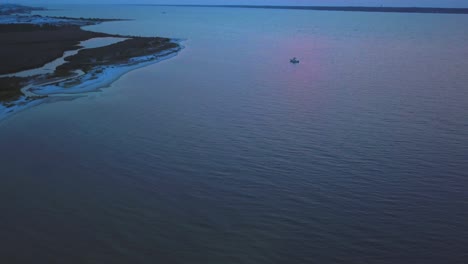 Ein-Einsames-Boot-Genießt-Die-Stille-Des-Meeresrauschens-Bei-Sonnenuntergang,-Gesehen-Von-Einer-Drohne-In-Der-Luft
