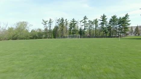 Reverse-moving-shot-across-a-soccer-field-through-a-ripped-part-of-the-opposing-net-in-the-goal