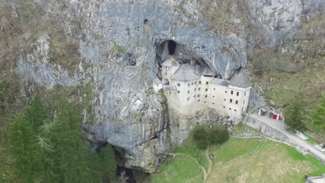 Drone-shot-of-mysterious-Predjama-castle,-built-in-a-cave-mouth-in-the-mountains-of-Slovenia