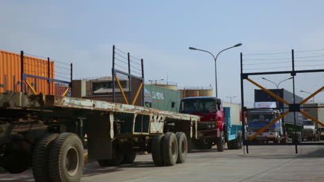Trucks-entering-into-the-port,-long-vehicle-trallers-are-moving-on-the-road-of-a-port,-camera-passing,-close-up-view