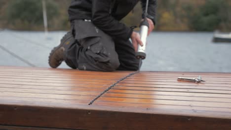Carpenter-sealing-roof-planking-of-boat-cabin-with-sealant-gun