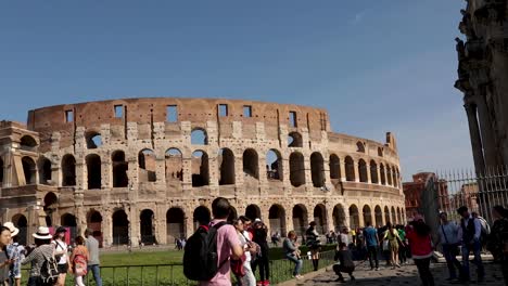 Toma-Panorámica-Del-Coliseo-De-Roma-Con-Turistas-Caminando-En-Primer-Plano.