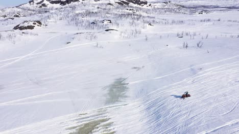 Luftaufnahme-Einer-Gruppe-Von-Menschen-Auf-Schneemobilen-In-Einer-Verschneiten-Berglandschaft