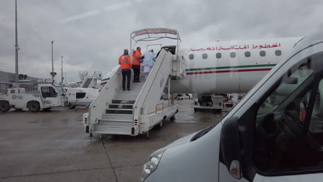 Paris-Orly-airport,-seen-from-a-passenger-shuttle-in-front-of-a-Royal-Air-Maroc-plane,-employees-helping-an-elderly-person-board-the-plane