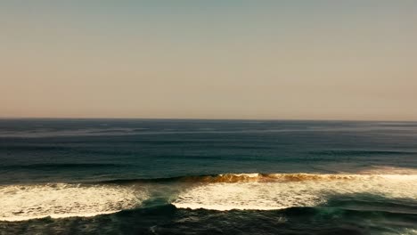 Aerial-footage-filmed-with-a-drone-overlooking-the-beach-and-sea-of-crashing-waves-with-a-deep-blue-ocean-on-the-Bluff-in-Africa-southern-hemisphere