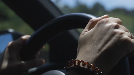 Woman-driving-a-car-on-the-motorway,-closeup-of-her-Hands-and-steering-wheel