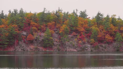 Panning-shot-over-a-lake-of-a-hillside-with-board-walks-and-lookouts-in-the-late-fall-in-Quebec,-Canada