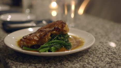Roast-Chicken-and-Rapini-plated-on-a-counter-at-an-upscale-restaurant-is-sliced-by-customer