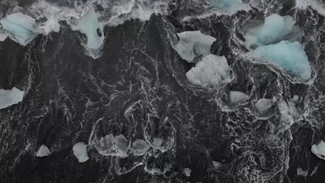 Slow-motion-shot-from-above-icebergs-on-black-sand-beach