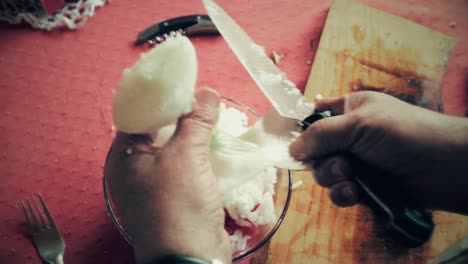 first-person-from-the-top-view-of-hands-cutting-a-onion-in-small-pieces-to-make-salad