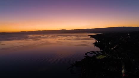 Flying-high-along-the-coast-of-Lake-Léman-with-beautiful-sunset-colors-Lutry,-Vaud---Switzerland