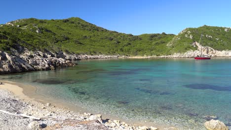 Sanfte-Schwenkaufnahme-Einer-Segelyacht-Auf-Dem-Kristallklaren-Wasser-Des-Strandes-Von-Porto-Timoni-Auf-Der-Insel-Korfu