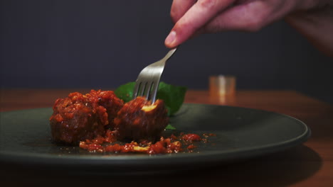 Side-View-of-a-Man-eating-Meatballs-in-Tomato-Sauce,-well-presented-dish-and-fine-dining-experience