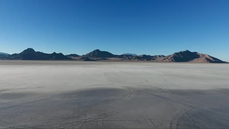 An-aerial-drone-shot-reveals-smooth-water-covering-the-white-slat-of-the-Bonneville-Salt-Flats-and-distant-mountains