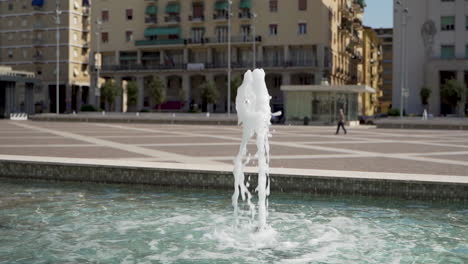 Slowmotion-dolly-of-single-fountain-in-the-middle-of-town-square