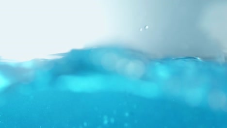 Die-Saubere-Wasseroberfläche-In-Zeitlupe-Füllt-Den-Bildschirm-Mit-Wasserspritzern-Shop-Der-Wassertropfen-Und-Die-Wellenförmige-Flüssigkeitsoberfläche-Mit-Einer-Luftblase