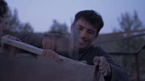 Afghan-refugee-man-hammers-nail-into-pallet-wood-timber-constructing-shelter