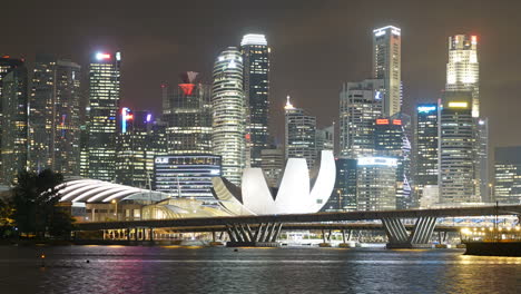 Singapur-–-Ca.-Zeitraffer-Verkleinerungsaufnahme-Der-Berühmten-Marina-Sands-Bay-Von-Singapur-Mit-Beleuchtetem-Theater,-Wolkenkratzer-Silhouette-Und-Belebter-Autobahnbrücke-Im-Vordergrund,-Nacht