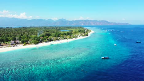 Paradise-tropical-island-with-long-white-beach-washed-by-blue-turquoise-lagoon-with-calm-clear-water-where-floating-many-touring-boats-in-Bali