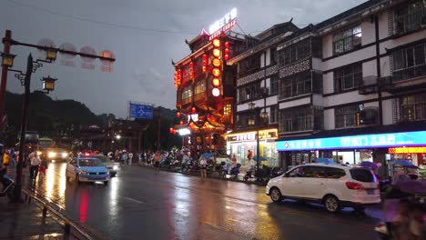 Wulingyuan,-China---August-2019-:-Bustling-life-with-cars,-traffic-and-lights-on-buildings-lit-at-night-at-a-busy-high-street-in-town-at-dusk
