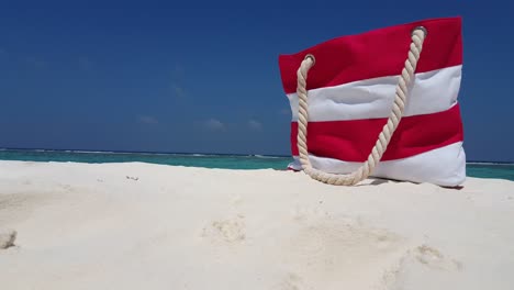Copy-space-of-travel-theme-with-a-stripped-summer-bag-standing-on-sandy-exotic-beach-with-sea-and-sky-background-in-Barbados
