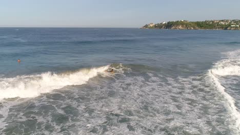 Aerial-shot-of-a-boogie-boarder-in-a-tube-barrel-wave-with-a-rainbow-in-Zicatela-beach-Puerto-Escondido,-Oaxaca
