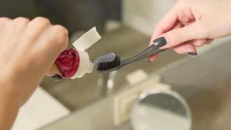 Close-up-scene-of-a-woman-who-is-putting-some-amount-of-toothpaste-on-a-toothbrush