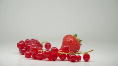 Reife-Rote-Johannisbeeren-Am-Stiel-Und-Eine-Köstliche-Erdbeere---Nahaufnahme