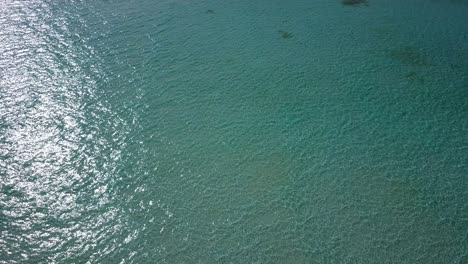 The-Clean,-Pristine,-Clear-Waters-Of-The-Maldives-Reflecting-The-Light-Of-The-Bright-Sun---Aerial-Shot